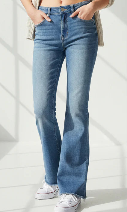 tween girl wearing blue washed out bootcut jeans on a light background